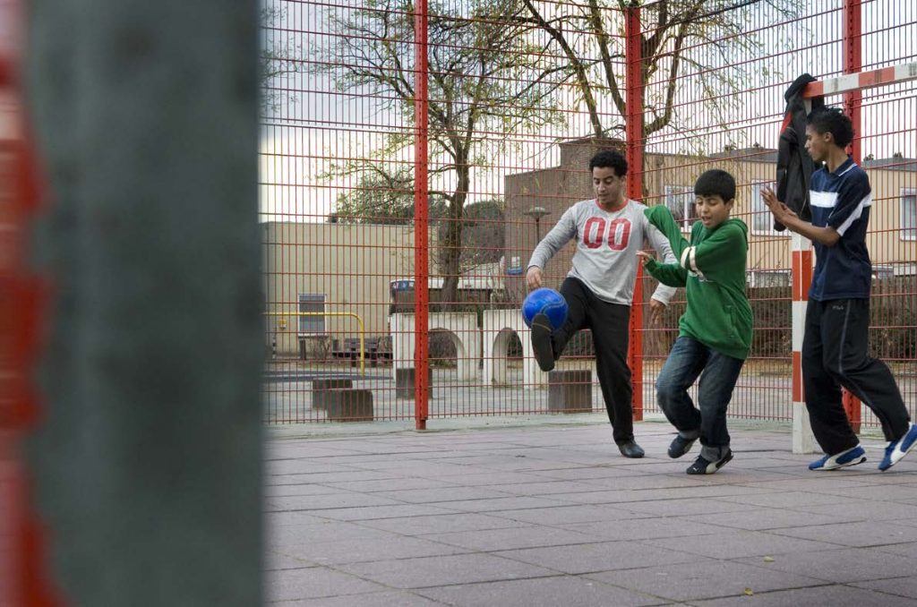 jongeren voetballen in een voetbalkooi